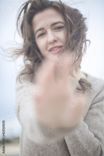 portrait of a beautiful sensual young woman, hair develops the wind, brunette with emotions, hands hair and face, seaside wind outside