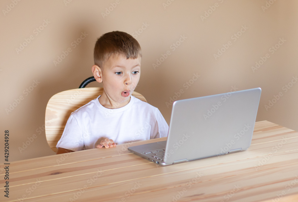 Little boy sitting at the laptop is surprised.