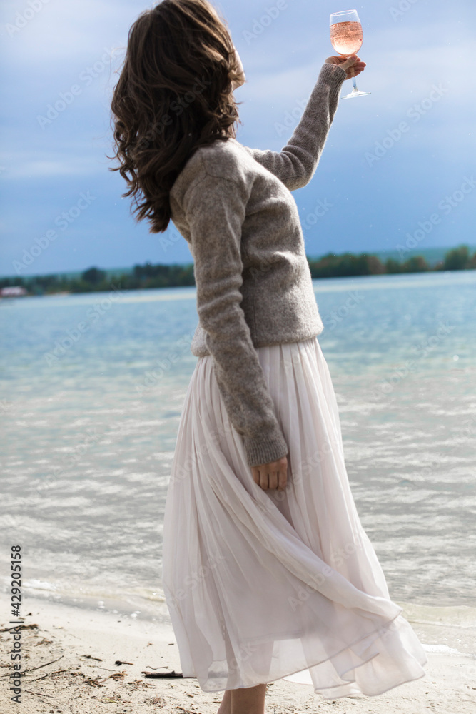 young beautiful brunette woman drinking rose wine in a glass on the street, wine tasting near the water, lake or sea young beautiful brunette woman drinking rose wine in a glass on the street, wine tasting near the water, lake or sea