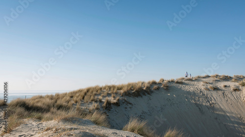 father and son climb dunes under blue sky on sunny day in spring