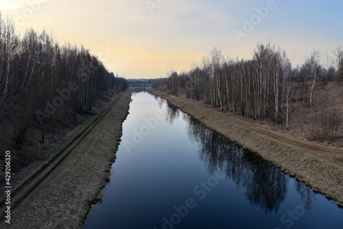 River channel on the background of woodland in the spring season at sunset of the day