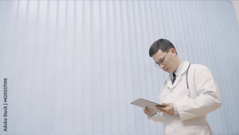Asian male therapist reading information on tablet, checking good test results Asian male therapist reading information on tablet, checking good test results