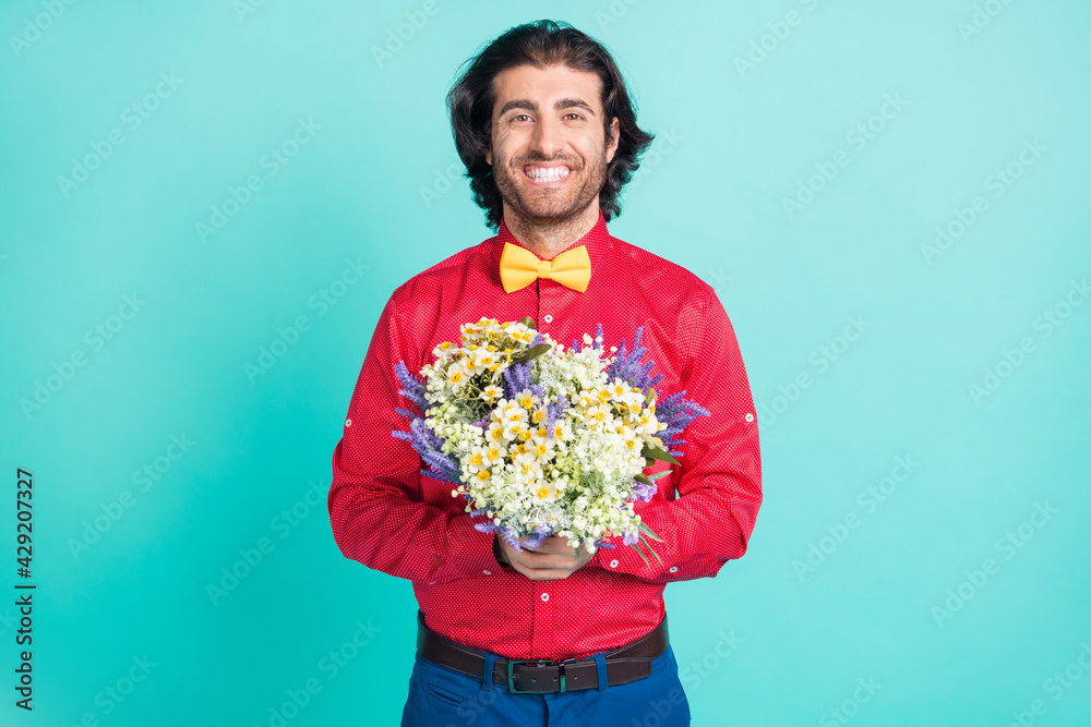 Photo of young handsome positive smiling gentleman give you bouquet of wildflowers isolated on turquoise color background Photo of young handsome positive smiling gentleman give you bouquet of wildflowers isolated on turquoise color background