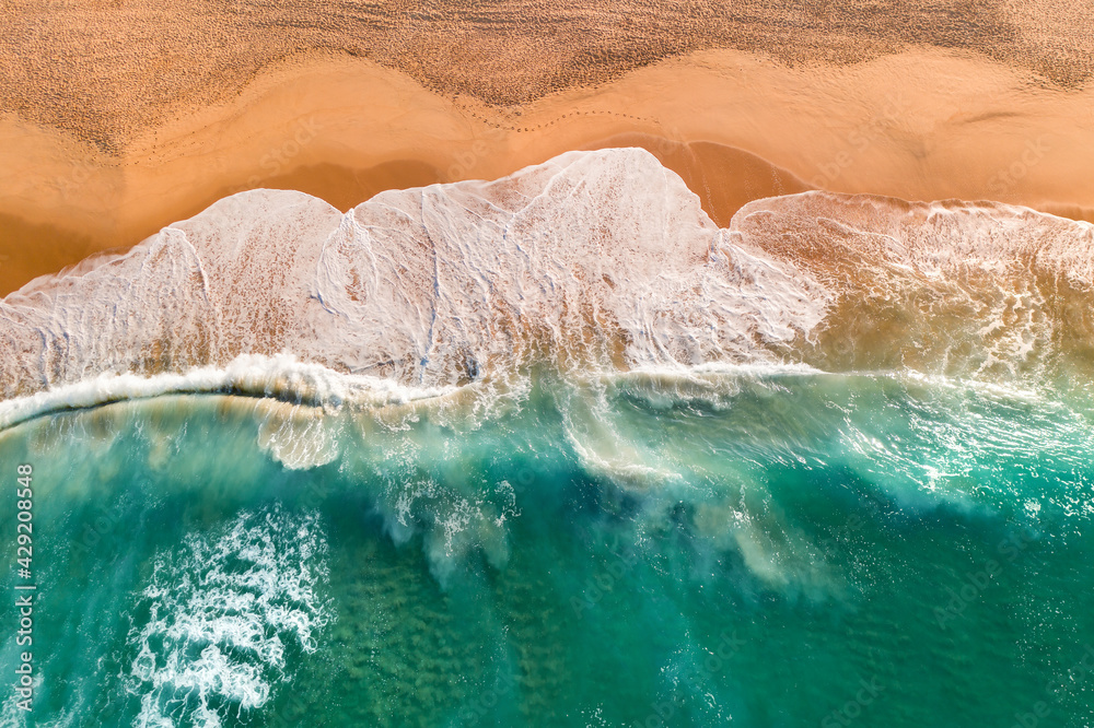Aerial view of Atlantic ocean sandy beach with breaking waves. Top view of sea coast with turquoise water