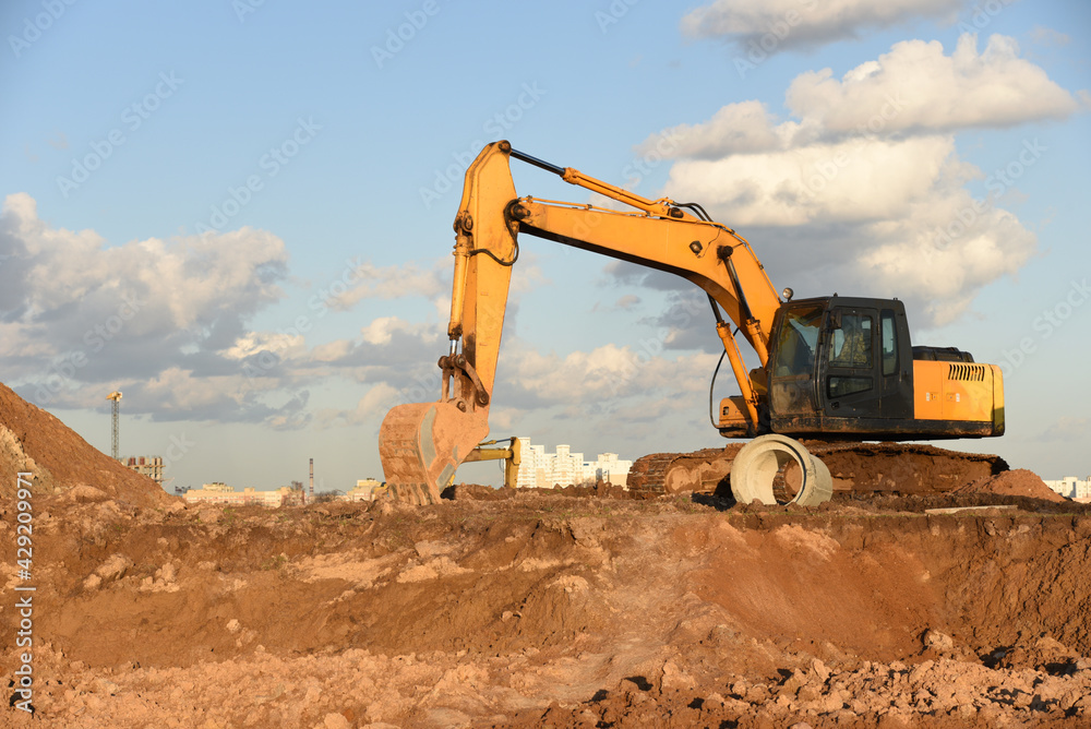 Excavator dig the trenches at a construction site. Trench for laying external sewer pipes. Sewage drainage system for a multi-story building. Digging the pit foundation. Excavator dig the trenches at a construction site. Trench for laying external sewer pipes. Sewage drainage system for a multi-story building. Digging the pit foundation.