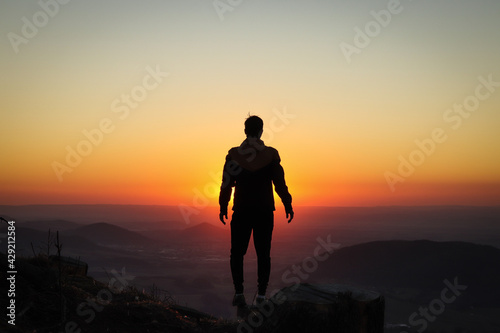 Silhouette of a young athlete who stands on a tree stump and is surrounded by a pounding ball of the setting sun. Add confidence. Ondrejnik  Beskydy mountains  czech republic