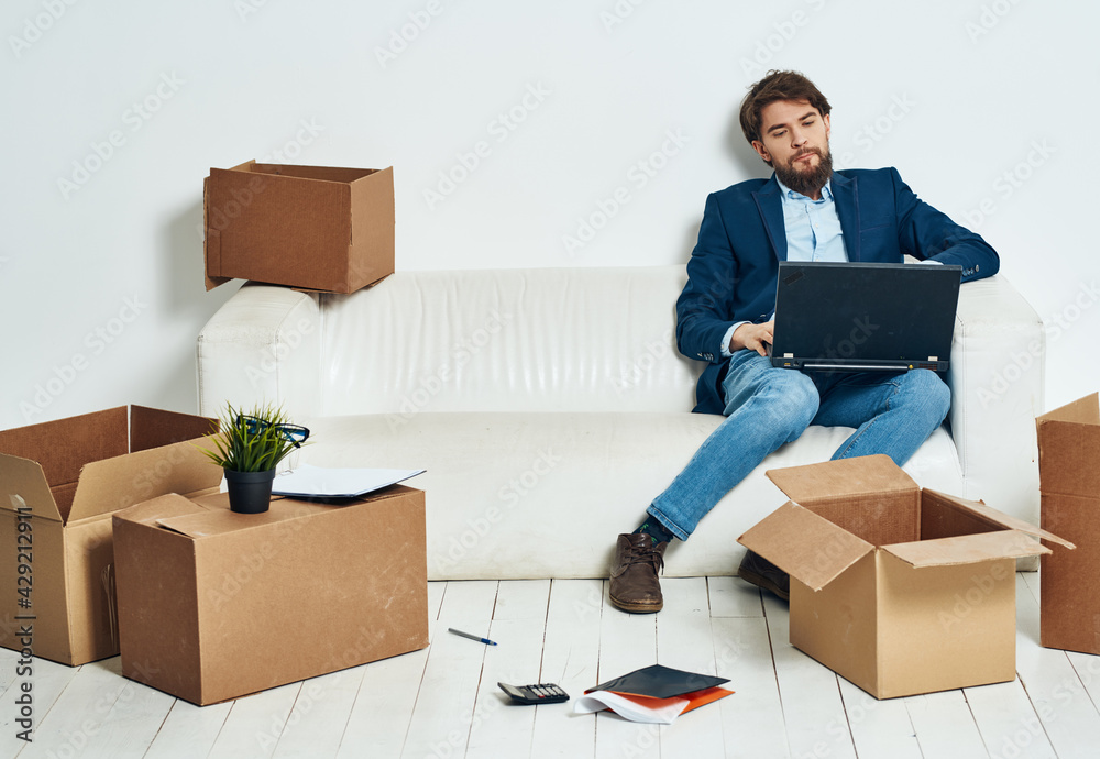 Man sitting on sofa with laptop office boxes with things work Man sitting on sofa with laptop office boxes with things work