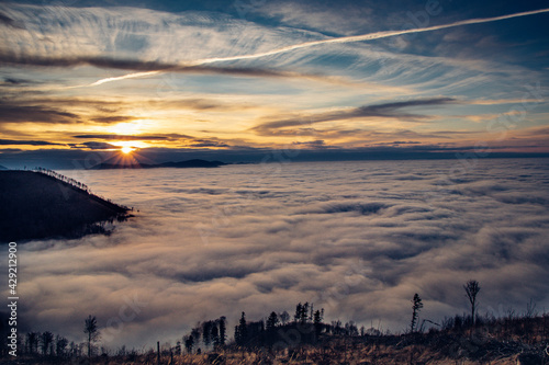 last rays of the sun cross the clouds and go behind a high mountain and put the earth in the dark. View from Ondrejnik mountain  Czech Republic. Being above the clouds