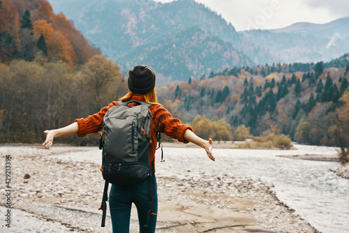 a traveler with a backpack in a sweater and jeans are resting in the mountains in nature near the river in autumn