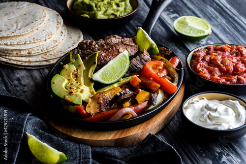 Принти на полотні Close up of a skillet filled with steak, peppers and avocados to make fajitas, surrounded by other toppings
