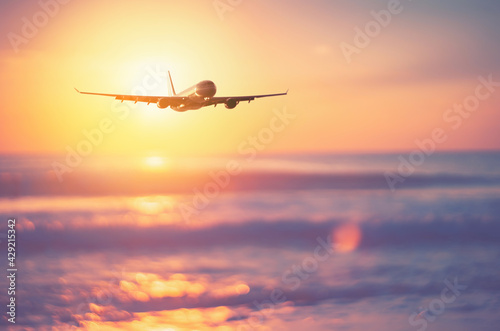 Airplane flying over tropical beach with smooth wave and sunset sky abstract background.