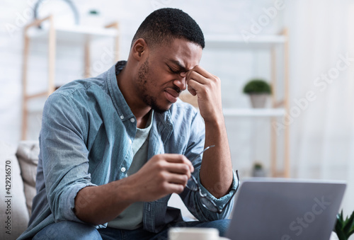 African Man Massaging Nosebridge Tired After Work On Computer Indoors