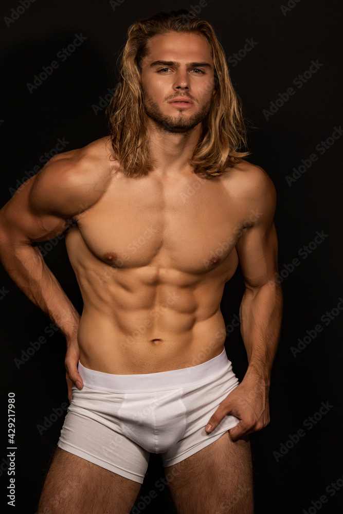 Sexy sport muscle strongface blond guy with long hair in white underwear on black isolated font background Sexy sport muscle strongface blond guy with long hair in white underwear on black isolated font background