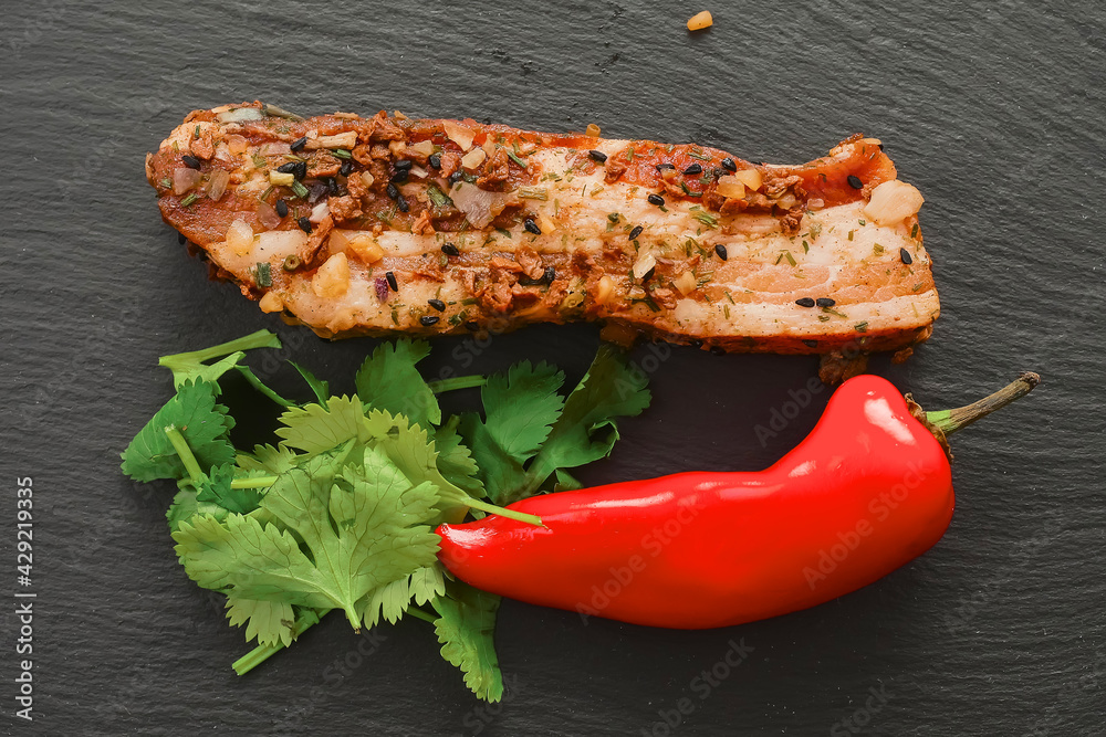 Raw Asian style marinated pork belly slice with red pepper and coriander on black stone board. Meat with herbs and spices. Meat industry product. Top down view Raw Asian style marinated pork belly slice with red pepper and coriander on black stone board. Meat with herbs and spices. Meat industry product. Top down view