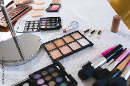 Selection of makeup brushes, sponges, eye shadows, lipstick,face powders and a mirror on a table top