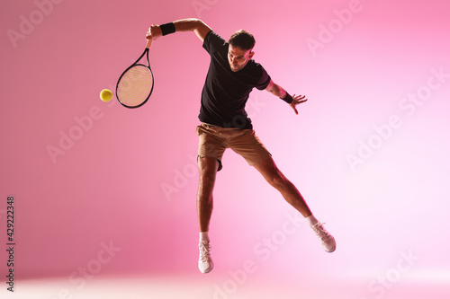 Young caucasian man playing tennis isolated on pink studio background, action and motion concept © master1305