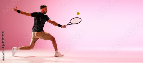 Young caucasian man playing tennis isolated on pink studio background, action and motion concept © master1305