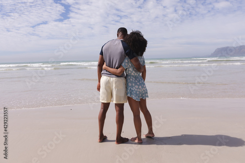 African american couple standing and embracing at the beach