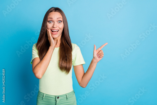 Photo portrait girl amazed pointing empty space touching cheek isolated vibrant blue color background