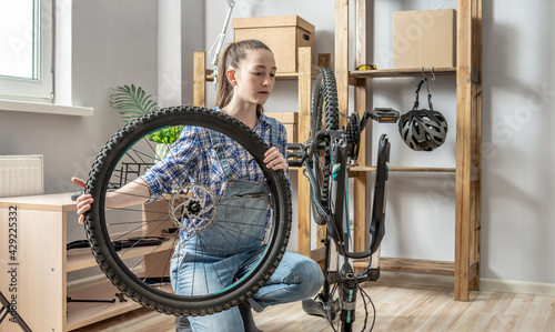 Woman fixing a mountain bike in a workshop. Concept of preparation for the new season, repair and maintenance