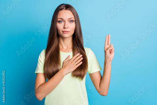 Photo of young attractive woman confident serious hand on chest make promise oath swear isolated over blue color background