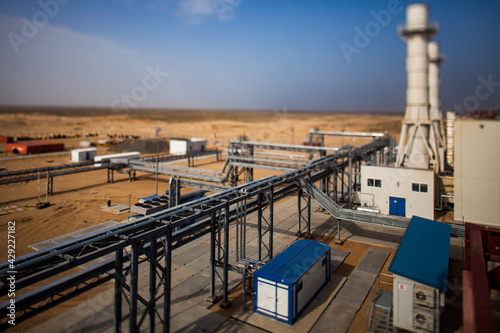 Kzylorda region/Kazakhstan - May 01 2012: Modern gas power plant in desert. Blurred picture with tilt-shift effect. Pipeline in focus. Dark sky and yellow sand background.
