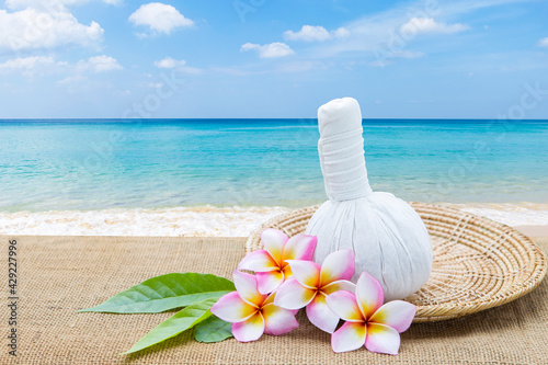 Herbal massage ball and plumeria flower over beach background, spa and wellness concept, rexlax by the sea, summer holiday and vacation 