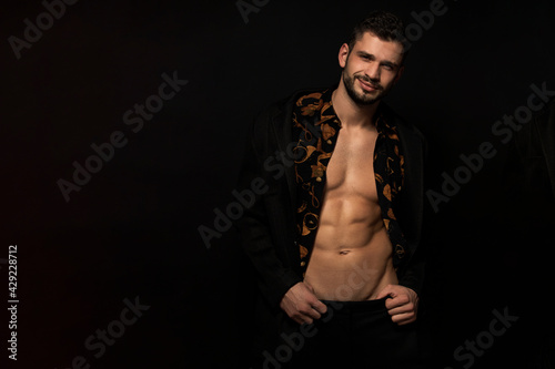 Muscle strong beautiful stripped male model in black pants and vintage shirt on black isolated font background