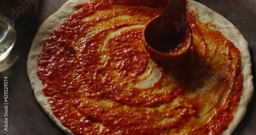 Chef is spreading  tomato sauce on pizza dough. Cooker making pizza with a traditional recipe in the kitchen, 4k footage
