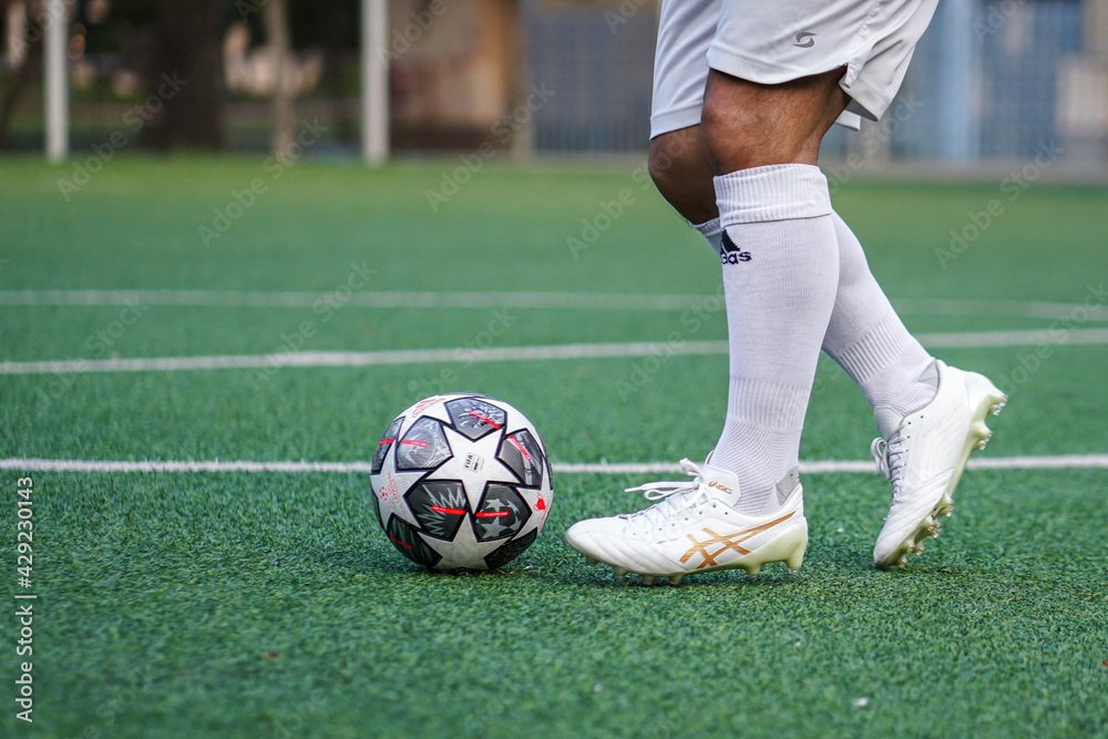 Bangkok, Thailand - April 2021: A football player who is wear Asics  football shoe in white color is training dribbling ball on local turf  pitch. Selective focus. Stock Photo | Adobe Stock