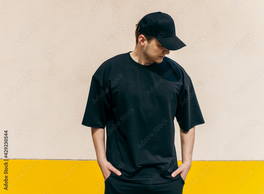 Man wearing black blank t-shirt and a black baseball cap with space for ...