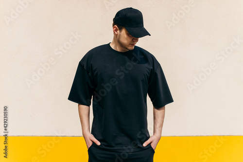 Εκτύπωση καμβά Man wearing black blank t-shirt and a black baseball cap with space for your logo or design