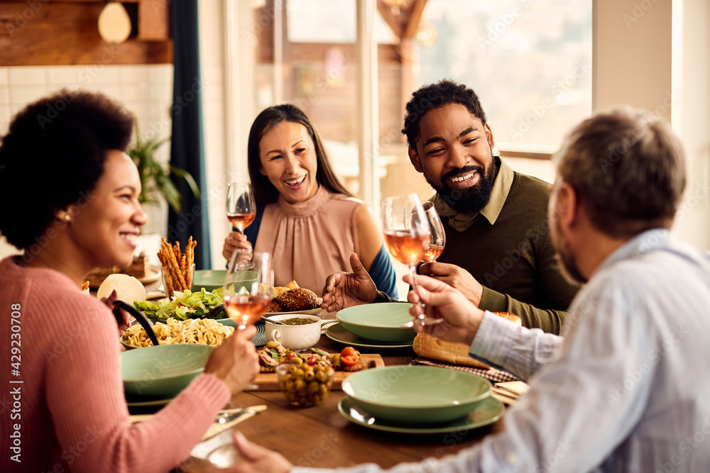 Happy black man having fun while talking with is friends during a meal at dining table. Happy black man having fun while talking with is friends during a meal at dining table.