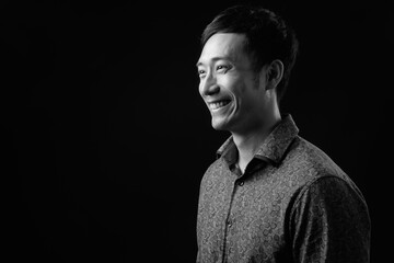 Young handsome Asian businessman against black background
