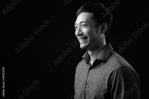 Young handsome Asian businessman against black background