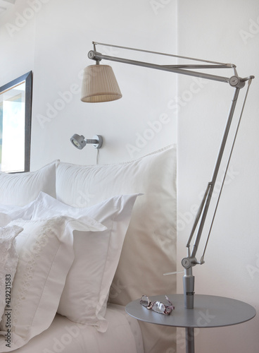 cama e cabeceira de cama, com almofadas brancas, candeeiro, óculos na mesinha de cabeceira. conforto. relax. © antonio
