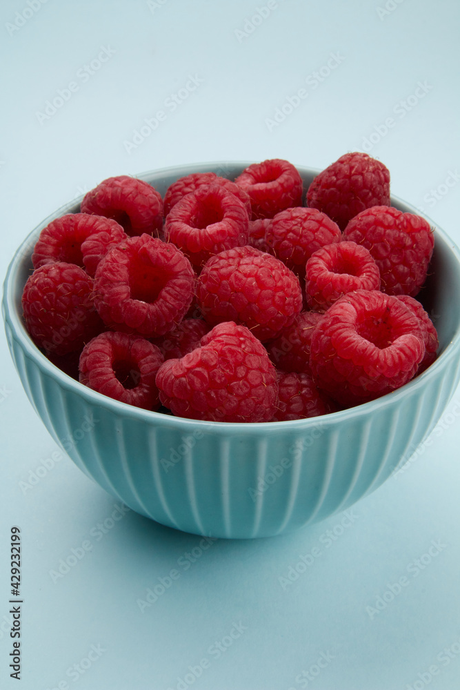 raspberries in a bowl on a colored background raspberries in a bowl on a colored background