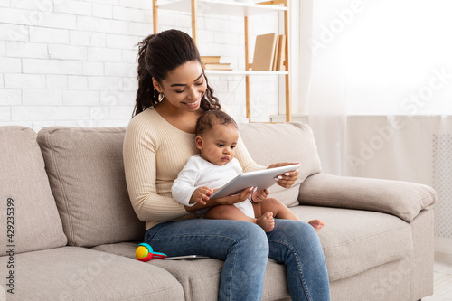 Cheerful Black Mommy Using Digital Tablet Holding Baby At Home