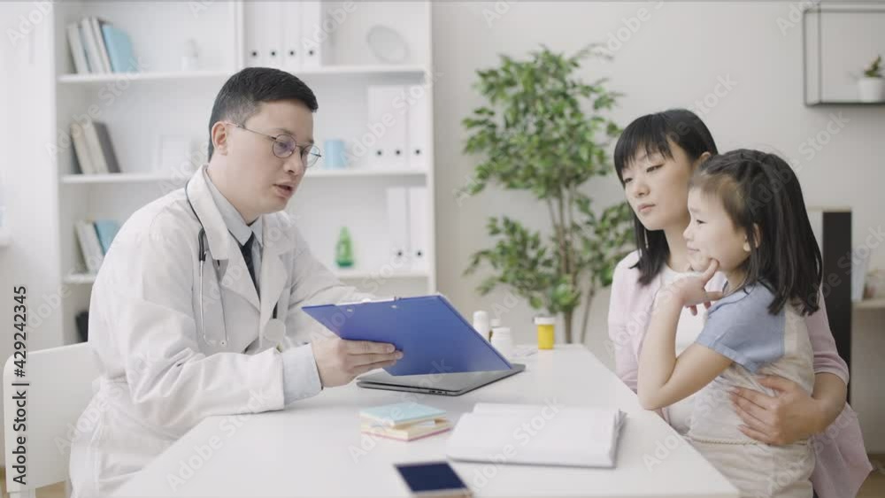 Doctor consulting asian woman and little girl in clinic, pediatric services Doctor consulting asian woman and little girl in clinic, pediatric services