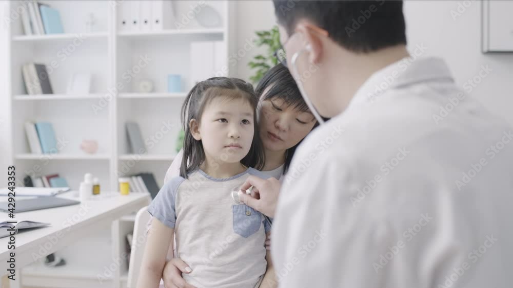 Chinese mother and daughter visiting hospital, family doctor examining patient Chinese mother and daughter visiting hospital, family doctor examining patient