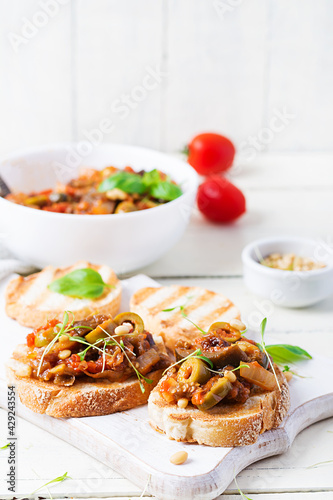 Traditional Italian Caponata and toast on a wooden white table. Sicilian caponata.