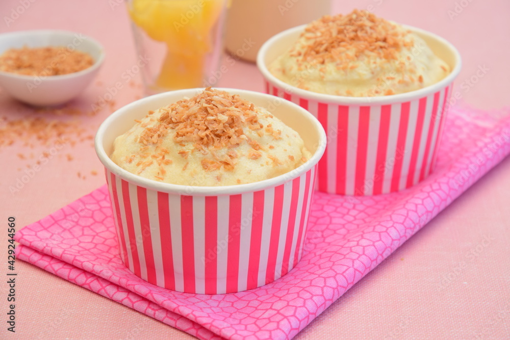 Pineapple coconut ice cream in cups topped with toasted coconut flakes Pineapple coconut ice cream in cups topped with toasted coconut flakes