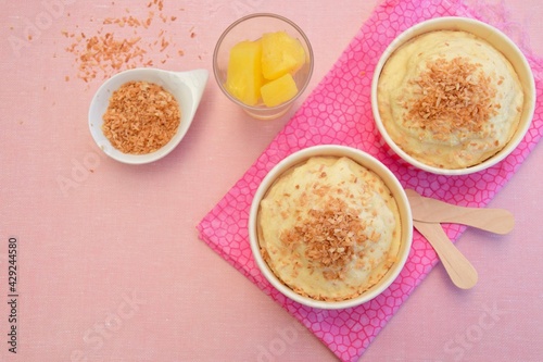 Pineapple coconut ice cream in cups topped with toasted coconut flakes