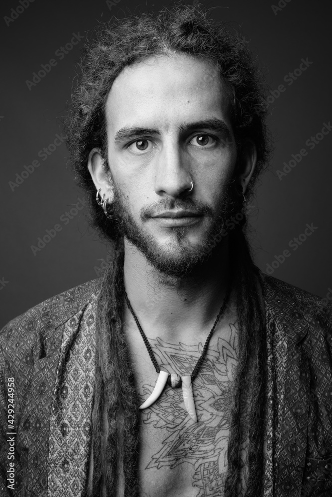 Fototapeta premium Young handsome Hispanic man with dreadlocks in black and white