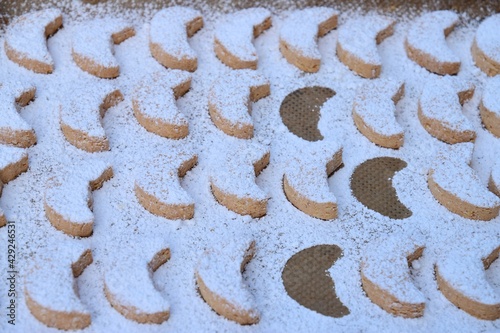 Putri Salju or crescent-shaped cookies coated with powdered sugar. Traditional Indonesian cookies to celebrate Eid al Fitr. Decorated with yellow flower on wooden background photo