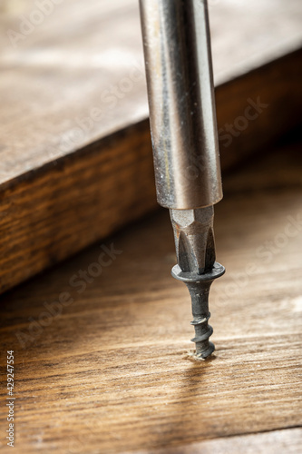 Self-tapping screw screwed into a wooden board close-up. Screw for wood