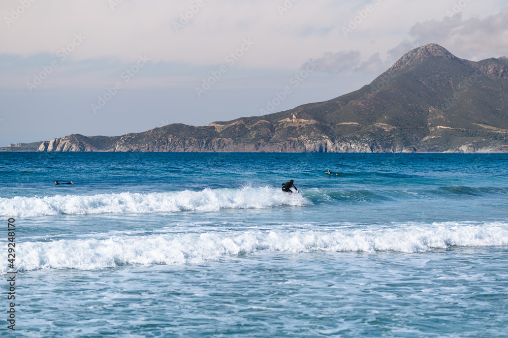 Surfer surfing at distance in a crystal clear water in Sardinia, Italy.