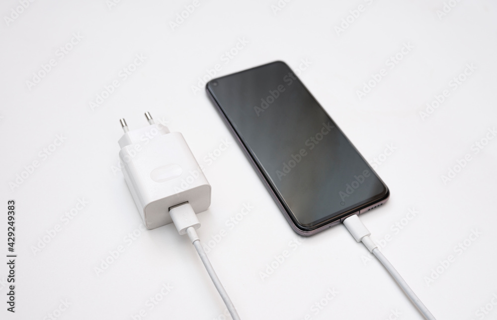 Charging a smartphone via a USB cable on a white background, top and side view. Silhouette of black smartphone with usb charging cable and power supply on white empty space.copy space. selective focus