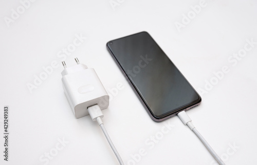 Charging a smartphone via a USB cable on a white background, top and side view. Silhouette of black smartphone with usb charging cable and power supply on white empty space.copy space. selective focus
