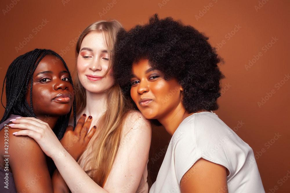 young pretty caucasian, afro, scandinavian woman posing cheerful together on brown background, lifestyle diverse nationality people concept young pretty caucasian, afro, scandinavian woman posing cheerful together on brown background, lifestyle diverse nationality people concept
